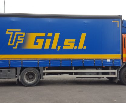 Camión mediano de transporte de mercancías aparcado en la puerta de una nave