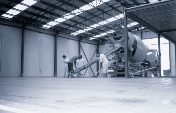 Grupo de hombres delante de una hormigonera dentro de una nave en construcción