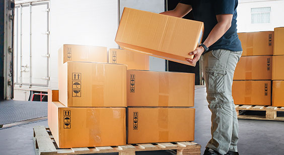 Trabajador de empresa de transportes apilando cajas sobre un palet