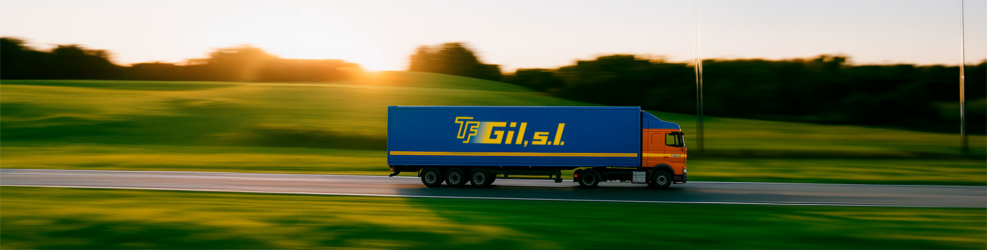 Vista lateral de un trailer en una carretera rodeada de prados