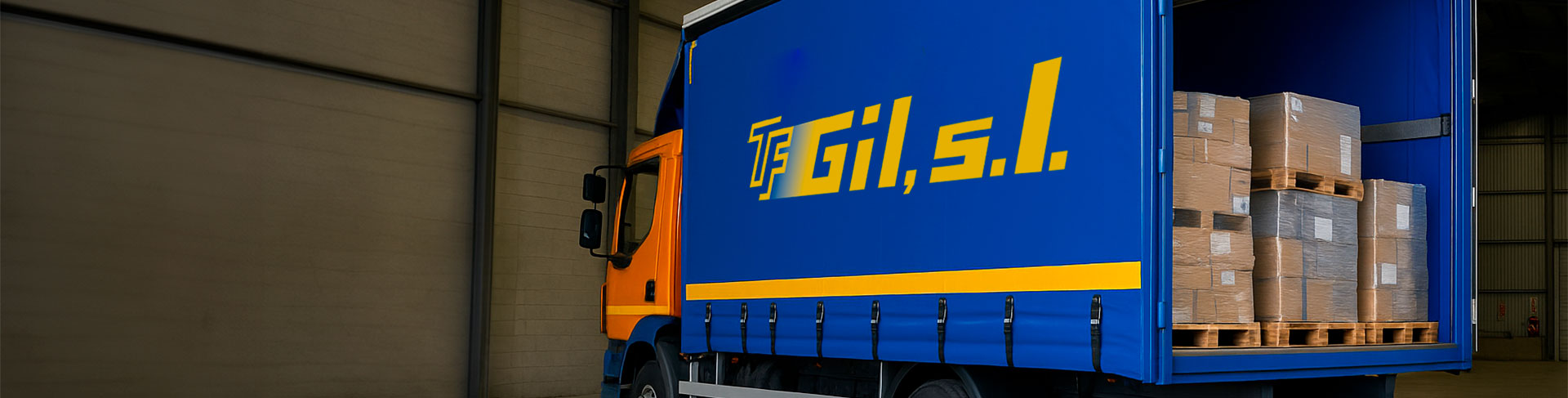 Camión aparcado dentro de una nave, con la puerta trasera abierta y mostrando cajas en el interior